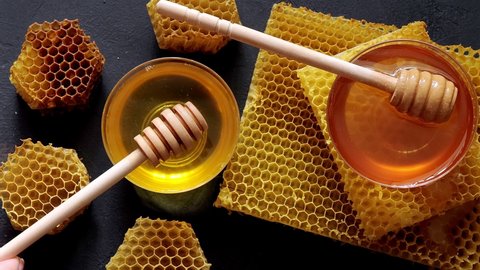 Honey dripping, pouring from a wooden spoon. Liquid fresh golden honey. Honeycombs. Healthy organic honey.