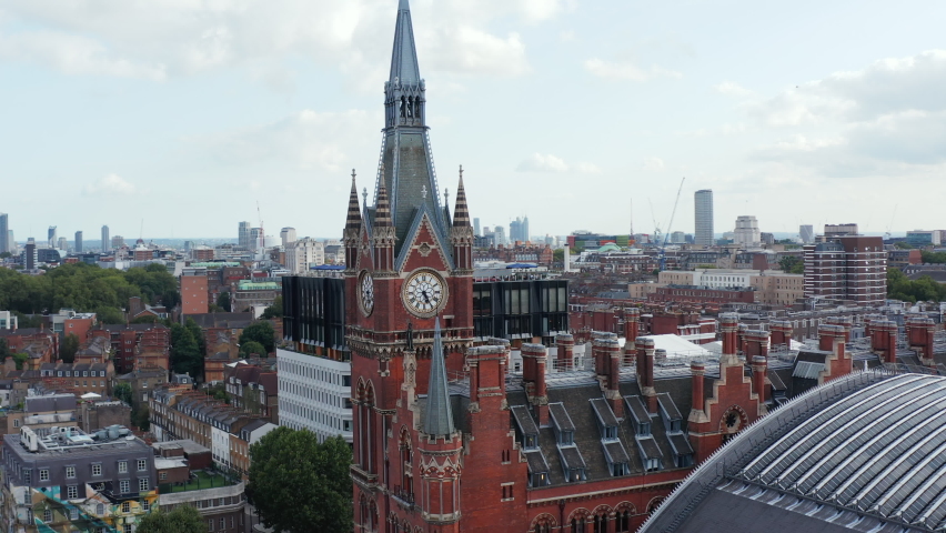 Beautiful decorated brick clock tower as part of old brick St Pancras train station building. Modern downtown skyscrapers in background. London, UK Royalty-Free Stock Footage #1088866161