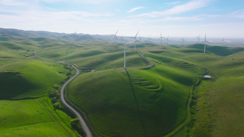 Aerial view of windmills farm for energy production on beautiful cloudy sunny sky at highland. Wind power turbines generating clean renewable energy for sustainable development, drone 4K California US