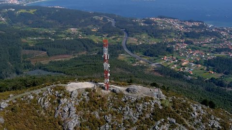 Aerial View Of Telecommunications Mast On Rocky Hillside In Miradoiro da Curota With Ria de arousa In background. Pedestal Up Tilt Down