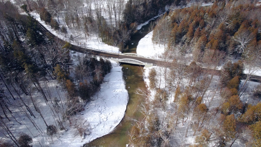 Scenic Bridge with winding road Spanning wide river set in a Winter Landscape with snow and Evergreen Trees