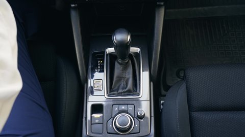 Woman controls auto, switch gears. Hand of person driver is shifting the automatic transmission in car close up. Female driving and changing gear. Top view.