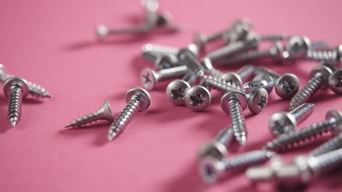 Close up shooting of parts of carpentry screws with cross head. screws on the table. industry background. 4k footage.