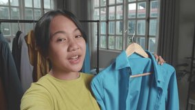 Close Up Of Asian Young Girl Online Seller Recommending A Shirt And Recording Video While Selling Clothes At Home
