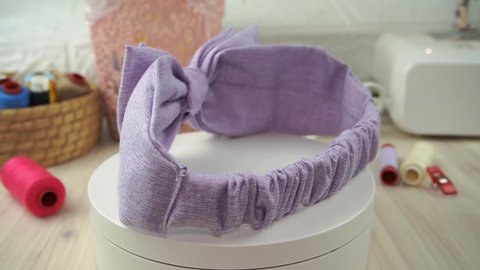 A headband with bow pattern made out of cotton fabric in soft lavender color, great as hair accessories for babies and kids.
