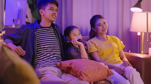 relax casual laugh movie reaction,asian family stay together watching horror movie at night in living room happiness smiling joy expression,asian mom dad daughter spending weekend together at home