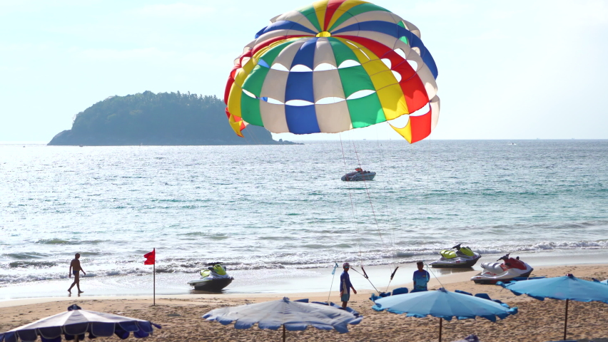 Parasailing Phuket Thailand slow motion flying sky during sunset mountain. Activity sports beach relax weekends daytime. Summer vacation and holiday island daylight. camera 4K copy space 2022.