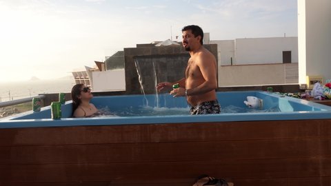 a wedding couple dancing and drinking Pilsen beer in a swimming pool in a house beach at sunset in 4k - Punta Hermosa, Peru - January 2022