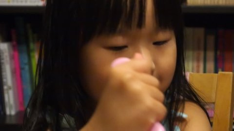 Beautiful asian toddler girls eating cake and blowing out candles