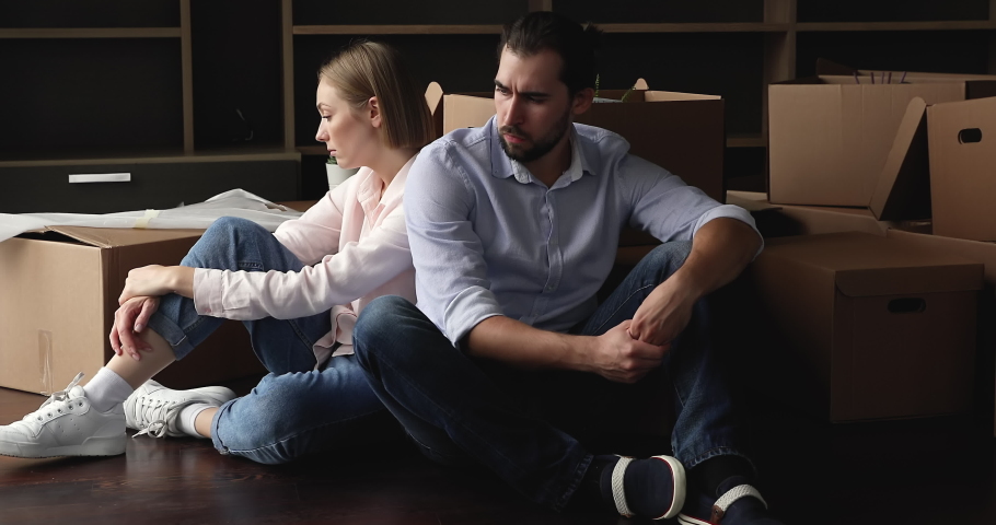 Tired unhappy married couple sit on floor with cardboard boxes, feel exhausted and unmotivated on moving day, lender seize home due borrower stopped make payments, foreclosure, owner eviction concept Royalty-Free Stock Footage #1088885325