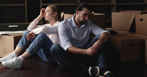 Tired unhappy married couple sit on floor with cardboard boxes, feel exhausted and unmotivated on moving day, lender seize home due borrower stopped make payments, foreclosure, owner eviction concept