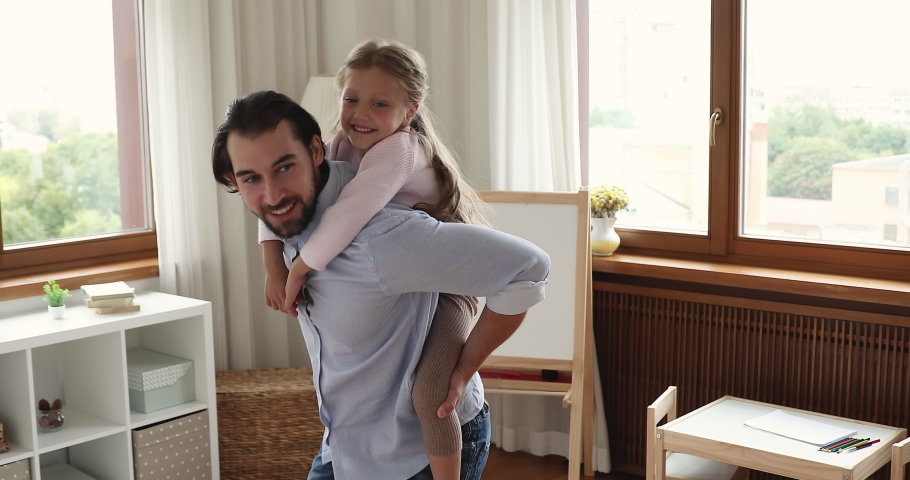 Lovely little 5s daughter piggyback father enjoy playtime together at home. Loving dad swirling spinning his preschool kid have fun in modern nursery, spend weekend leisure looking happy and carefree Royalty-Free Stock Footage #1088885353