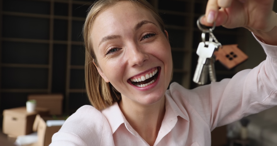 25s woman show keys from new own or rented house, smile staring at camera, looks joyful, close up webcam view during stream event or video call with friends or family. Tenancy, relocation day concept | Shutterstock HD Video #1088885411