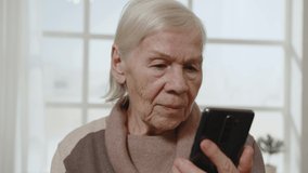 Elderly pensioner woman 80 years old using smartphone for online video communication.