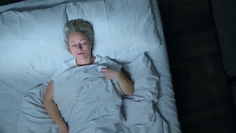 Sleeping man talking in his sleep in bed, top view. Woman suffering from parasomnia sleep disorders.