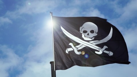 The pirate skull flag waving in wind, calico jack pirate symbol at cloudy sky.