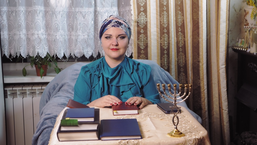 A female Reform Jewish rabbi in a traditional headdress teaches a Torah lesson. Medium plan