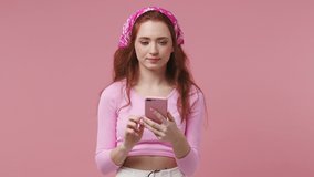 Young attractive woman in rose clothes bandana get video call using mobile cell phone doing selfie talk conducting pleasant conversation greet with hand isolated on pastel pink color background studio