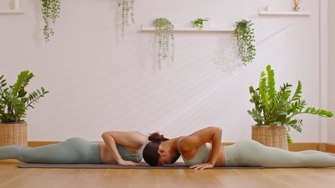 Calm of wellness Couple Asian young woman sit on yoga mat doing breathing exercise yoga cobra pose together.Yoga meditation of two healthy female relax and comfortable at cozy home.Healthy lifestyle