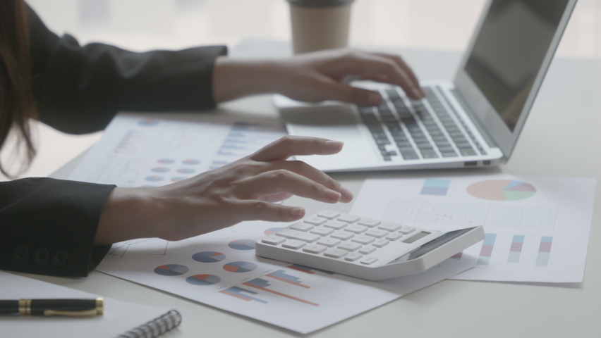 Close-up of businesswoman or accountant hand are calculating on calculator and texting on laptop about financial data report, accounting document on office table. Mood soft focus. - Powered by Shutterstock - Get 15% off with code: PIKWIZARD15
