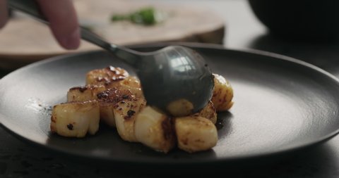Slow motion put roasted scallops on black plate