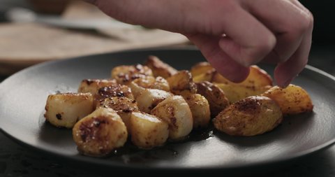 Slow motion put baked potato wedges to roasted scallops on black plate