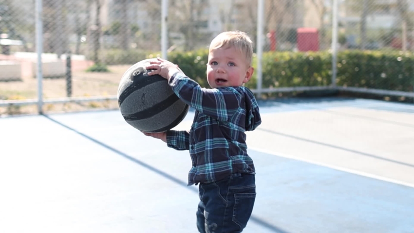 A little boy is holding a basketball ball, a child is learning to play basketball, a toddler is playing with a ball