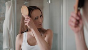 Caucasian woman brushing hair in the bathroom and looking at their loss on the brush. Shot with RED helium camera in 8K.