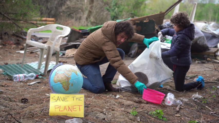 Europe, Father and 7 year old boy child  collect dirt polluting waste trash in nature. Clean up the environment and save Planet Earth from climate change and global warming - education and nature 