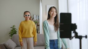 Asian young woman with her friend er created her dancing video by smartphone camera together To share video to social media application