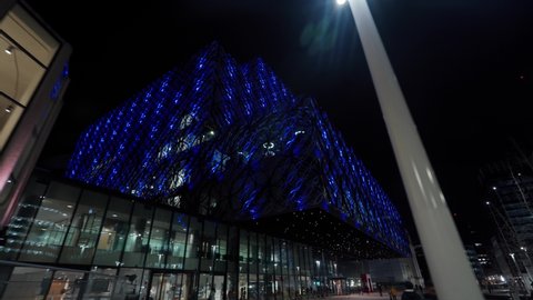 BIRMINGHAM, UK - 2022: Low upward looking aerial view of Birmingham library at night with blue lights