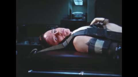 CIRCA 1960s - Astronaut Ed White lies on an examination table with a harness on, then walks up and down for a doctor.