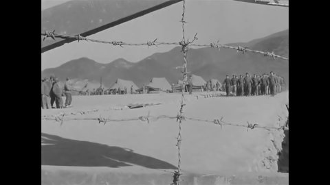 CIRCA 1951 - North Korean POWs are seen marching through a barbed wire gate.