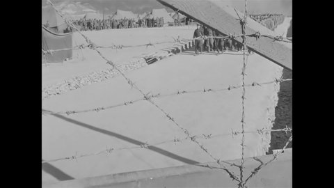 CIRCA 1951 - North Korean POWs are seen marching through a barbed wire gate.