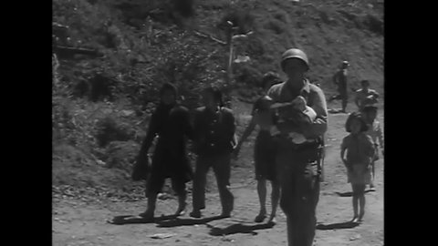 CIRCA 1945 - American soldiers help Filipino refugees of all ages, some wounded, navigate a hill.