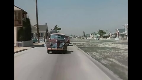 CIRCA 1940s - Cars drive through a neighborhood in Newport Beach, California.