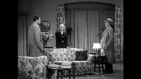 CIRCA 1933 - In this mystery movie, a detective investigating a murder interrogates a couple in their apartment.