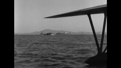 CIRCA 1950 - US Navy seaplanes taxi off the coast of Korea while guns are fired from the USS Missouri.