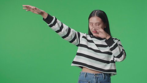 A Smiling Asian Woman Dabbing While Standing In Front Of Green Screen Background  

