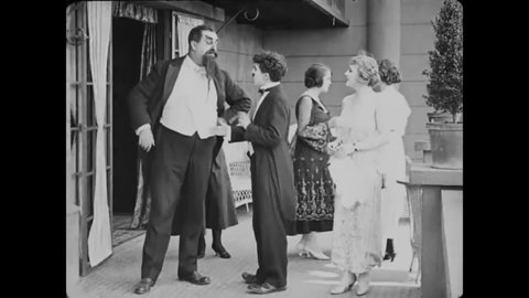 CIRCA 1917 - In this silent comedy, a man (Charlie Chaplin) fighting with his rival tricks him into kicking an aristocratic woman at a party.