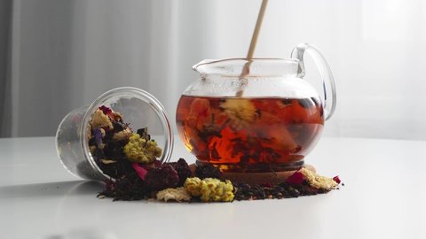 Tea in a glass teapot is spinning in a circle. Brew tea collection from flowers in a teapot. A scattering of dry tea leaves. tea movement