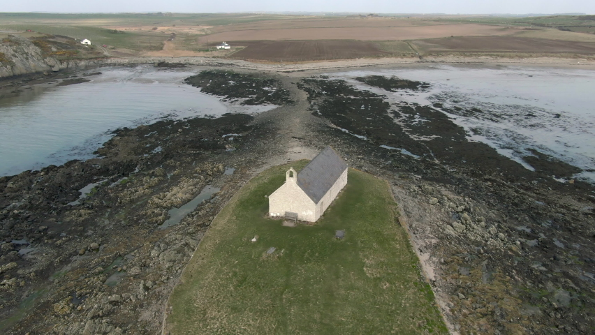 An aerial view of Eglwys Cwyfan church on an overcast day, flying left to right around the church, Anglesey, North Wales, UK