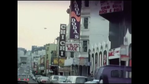 CIRCA 1960s - Cars drive past businesses advertising nude shows in San Francisco, California.