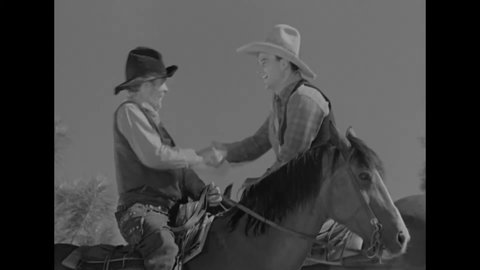 CIRCA 1934 - In this western film, a cowboy (John Wayne) greets an old friend on horseback.