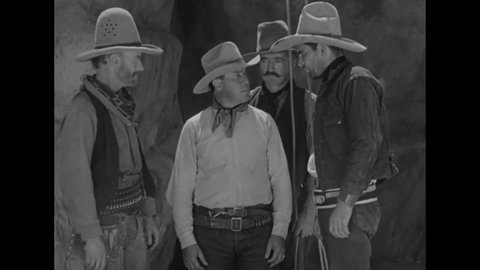 CIRCA 1934 - In this western film, a cowboy (John Wayne) uses a lasso to tie up his enemy and steals his horses.