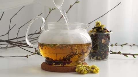 Brew tea leaves with hot water in a transparent glass teapot. natural flavored tea. Visualization of the brewing process. The movement of tea leaves in a circle. The teapot is on the table. 