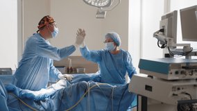 Male and female surgeon giving high-five to each other at hospital. Two handsome doctors are giving high five and smiling, standing in a modern operating room. Surgeon after operating in hospital. - Powered by Shutterstock - Get 15% off with code: PIKWIZARD15