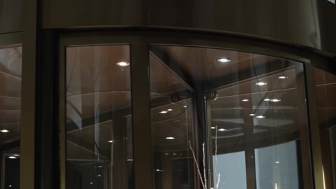 Close-up of brown glass revolving door with glossy surface and spotlights at night