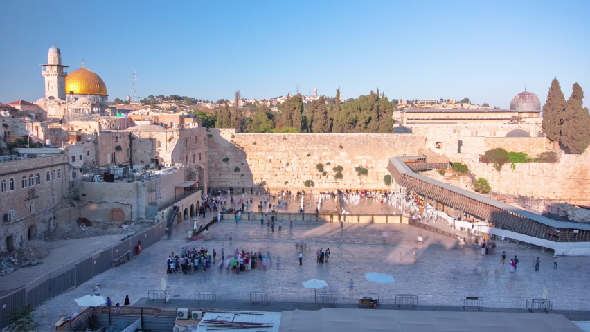 The Temple Mount in Jerusalem, including the Western Wall and the golden Dome of the Rock during Sunset timelapse. Shadow covering the wall. Many people at shabbat Royalty-Free Stock Footage #1088925491