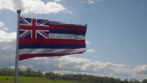 Hawaii flag on a flagpole waving in the wind in the sky. State of Hawaii in The United States of America